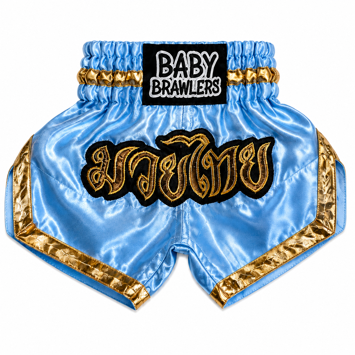 Light blue satin Muay Thai shorts with gold trim, featuring a black waistband patch with 'BABY BRAWLERS' text and a large gold embroidered Thai script patch on the front.