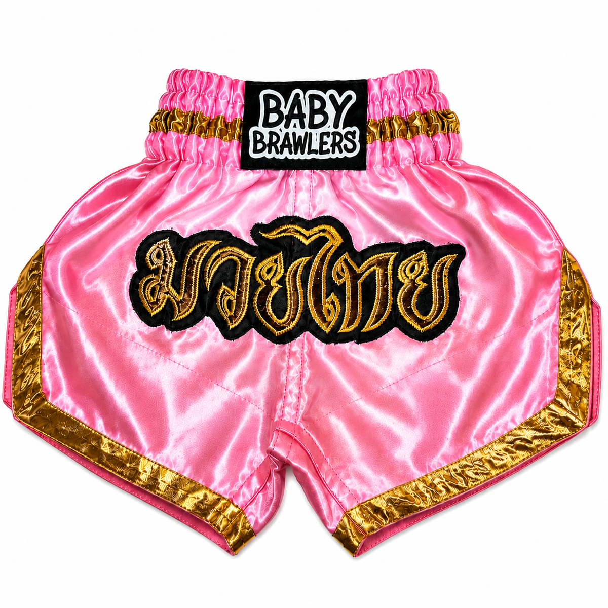 Pink satin Muay Thai shorts with gold and black trim, featuring a large gold Thai script patch on the front and a black waistband patch reading 'BABY BRAWLERS'.