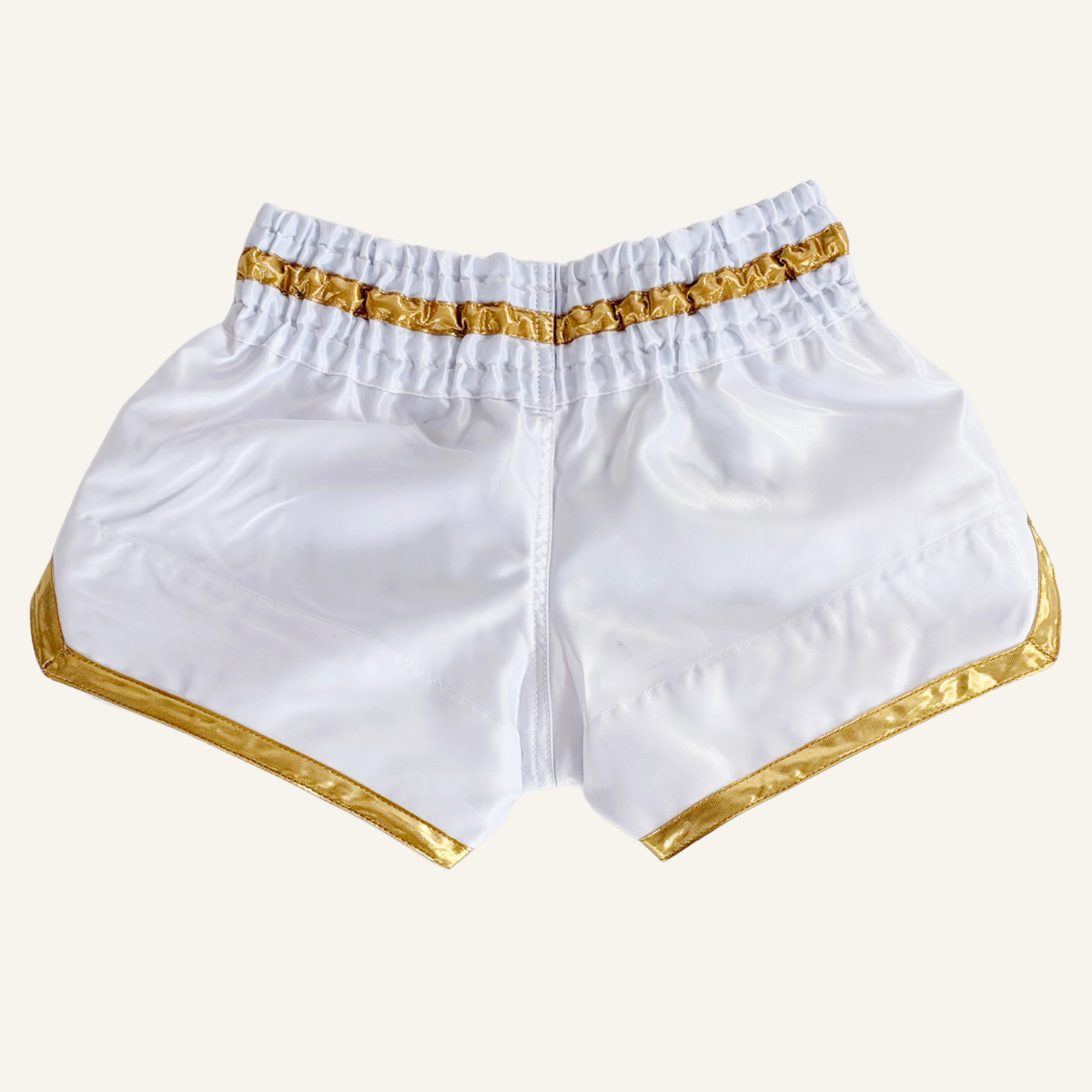 White satin martial arts shorts with shiny gold trim and an elastic waistband, shown flat against a white background.