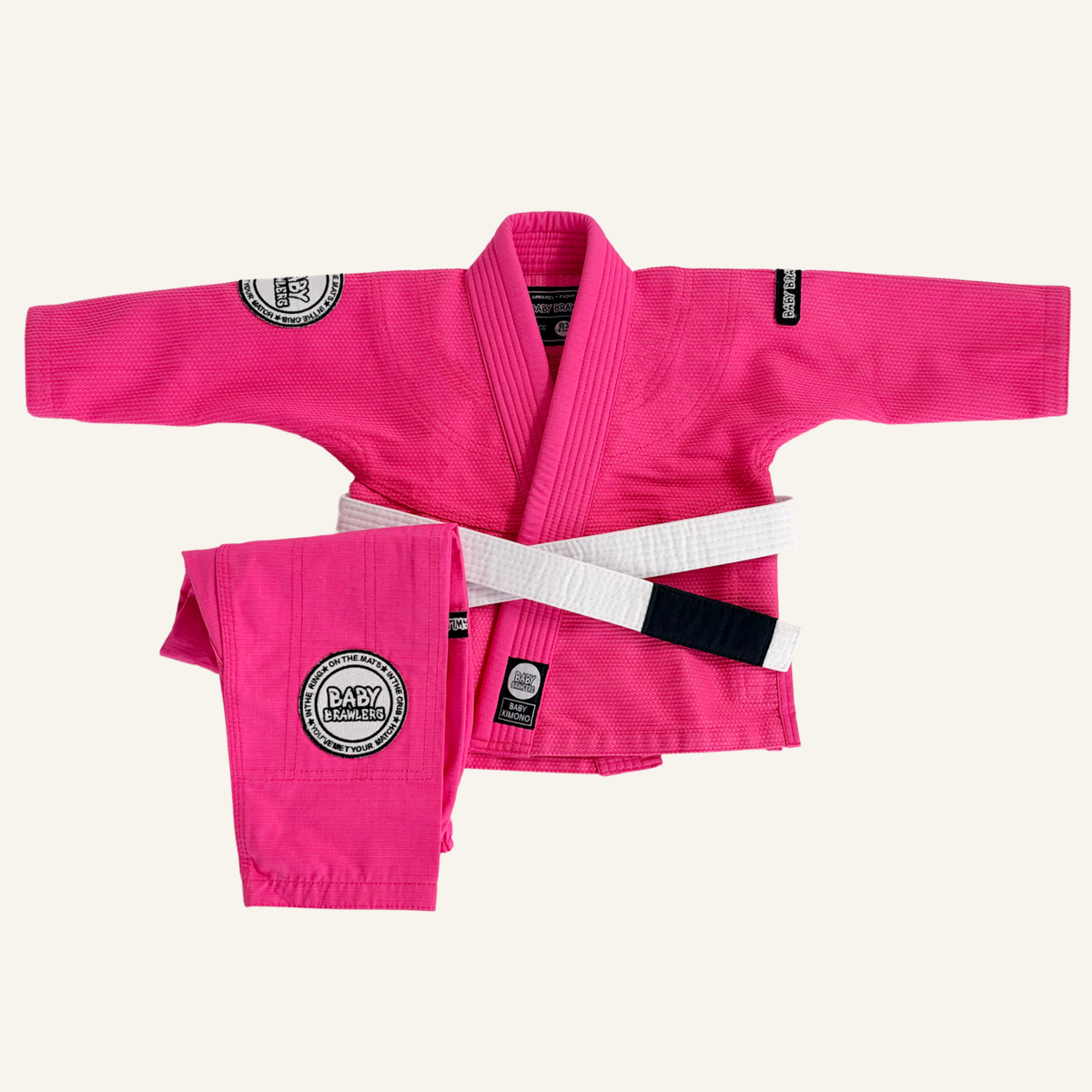 A bright pink martial arts uniform set laid out on a white background, including a gi jacket, matching pants, and a white belt. 
